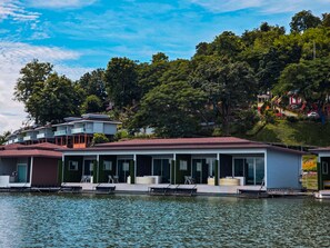 A waterfront property with multiple buildings, including a large house with a red roof and a smaller structure with a white exterior.