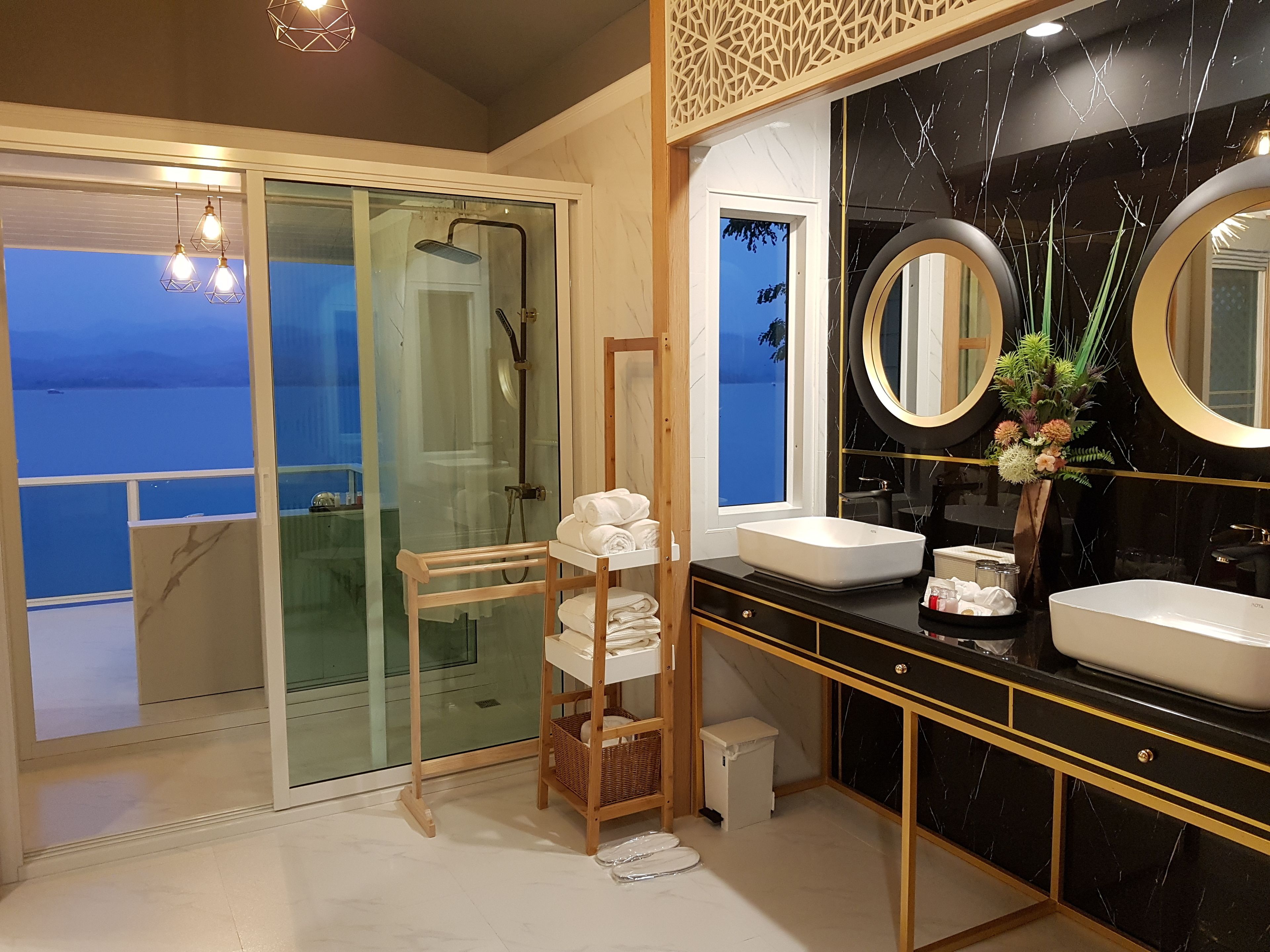 A modern bathroom with a glass shower door, two sinks, and a large mirror.