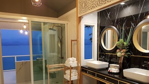 A modern bathroom with a glass shower door, two sinks, and a large mirror.