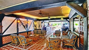 A cozy lounge area with wicker furniture, a tiled floor, and a ceiling fan.