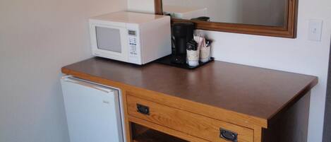 Una kitchenette compacta con microondas, cafetera y un refrigerador pequeño.