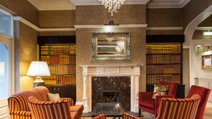 A library with bookshelves, a fireplace, and striped armchairs.
