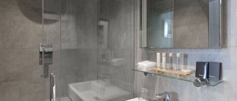A modern bathroom with a glass shower enclosure, a standalone bathtub, and a glass shelf with toiletries.
