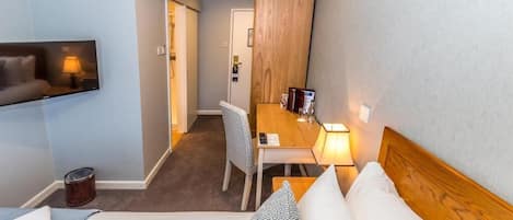 Habitación de hotel con cama, escritorio, silla, televisor y armario de madera.
