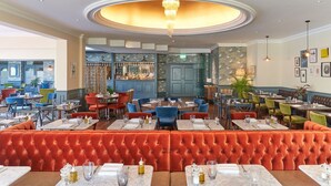A restaurant with a central bar area, multiple seating options including booths and tables, and a chandelier.