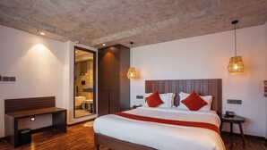 A modern hotel room with a wooden bed, a bench, a small table, and a nightstand.
