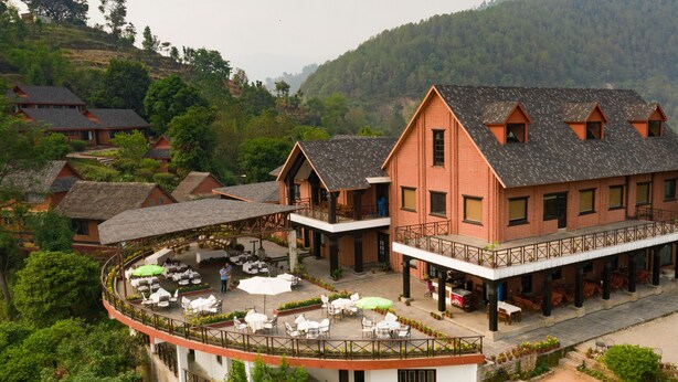 A hotel with a courtyard featuring outdoor seating, a covered area, and a view of the surrounding hills.