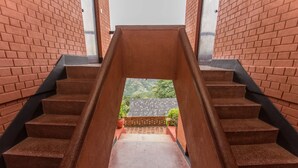 A staircase with a view of a brick wall and a garden in the background.