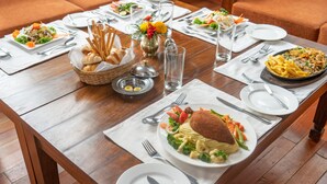A dining table set with various dishes, including pasta, salad, and bread, with a vase of flowers in the center.