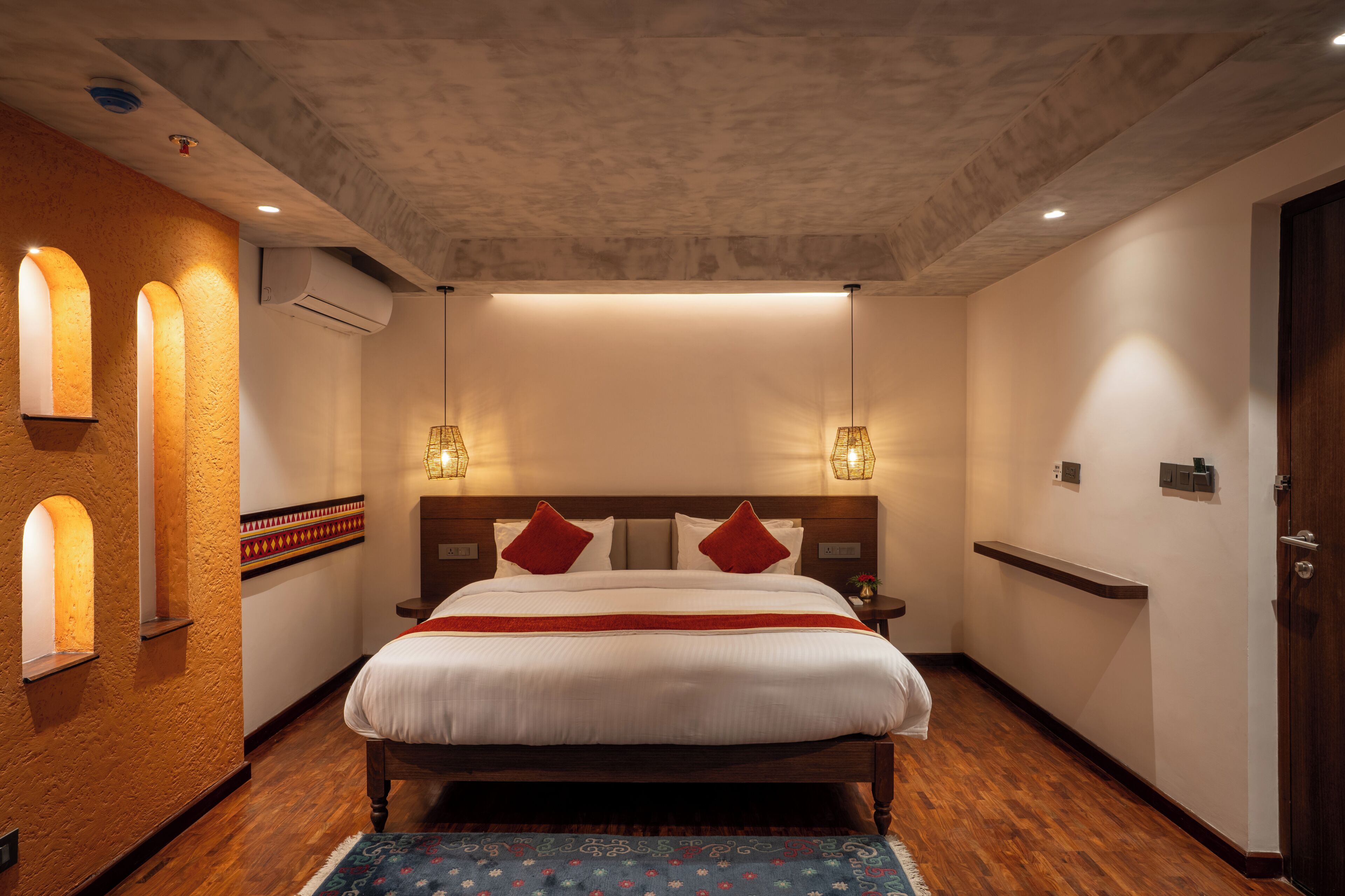 Camera d'albergo con un letto grande, due comodini, un condizionatore d'aria a parete e un pavimento in legno.