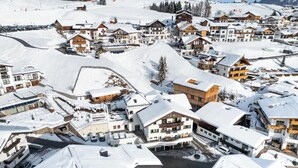 A snow-covered mountain resort with multiple chalet-style buildings, a ski lift, and a clear view of the surrounding snowy landscape. - Haus Sonnenterrasse (Fiss)