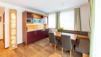 A modern kitchen with built-in appliances, a dining table with chairs, and a bench seating area.