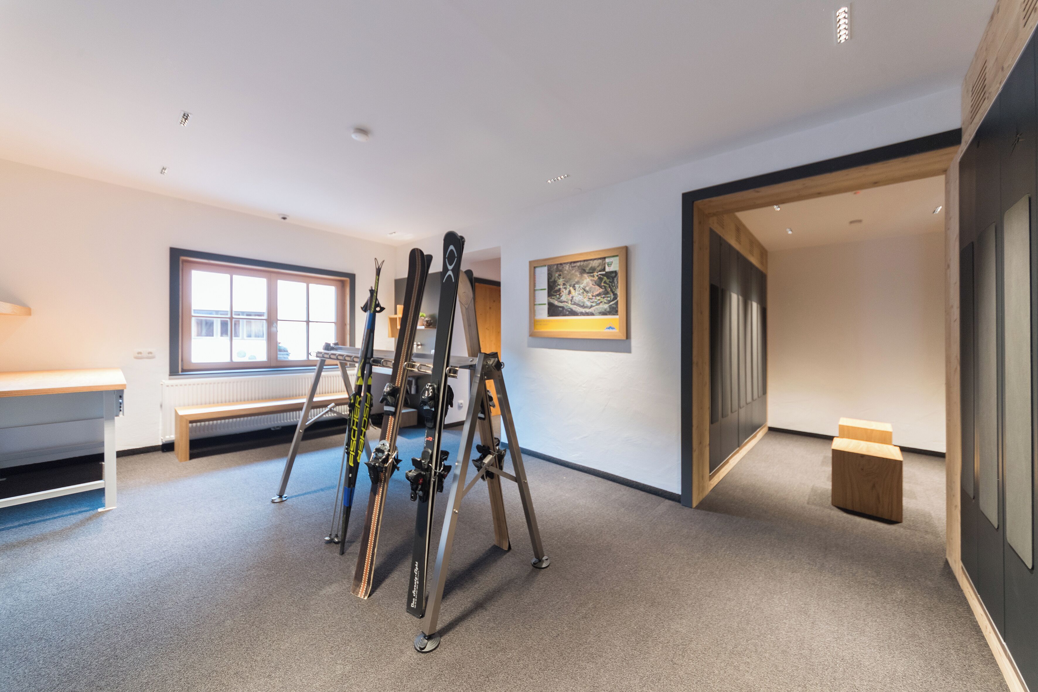 A room with a ski lift, a bench, and a framed picture on the wall.