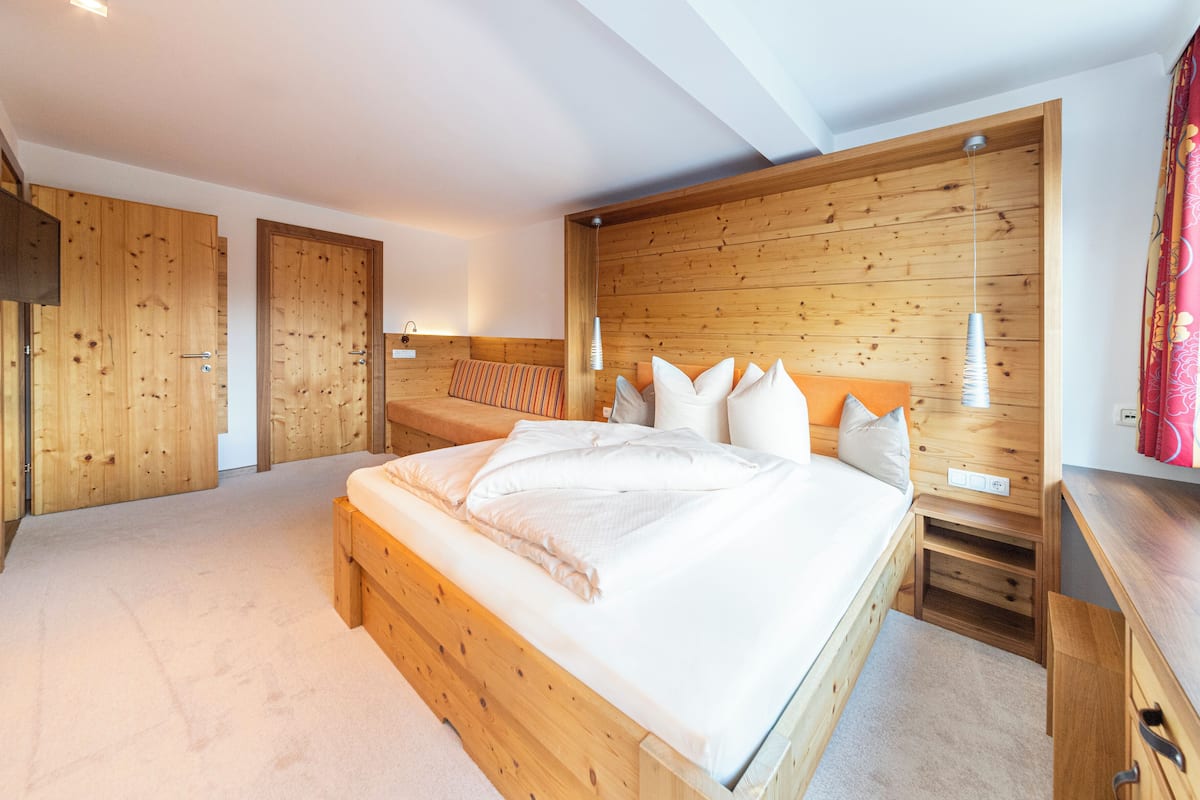 Quarto com cama de madeira, cabeceira de madeira, mesa de cabeceira e guarda-roupa de madeira.