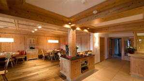 A wooden interior with a dining area, a central island with a vase, and a kitchen counter. - Haus Sonnenterrasse (Fiss)