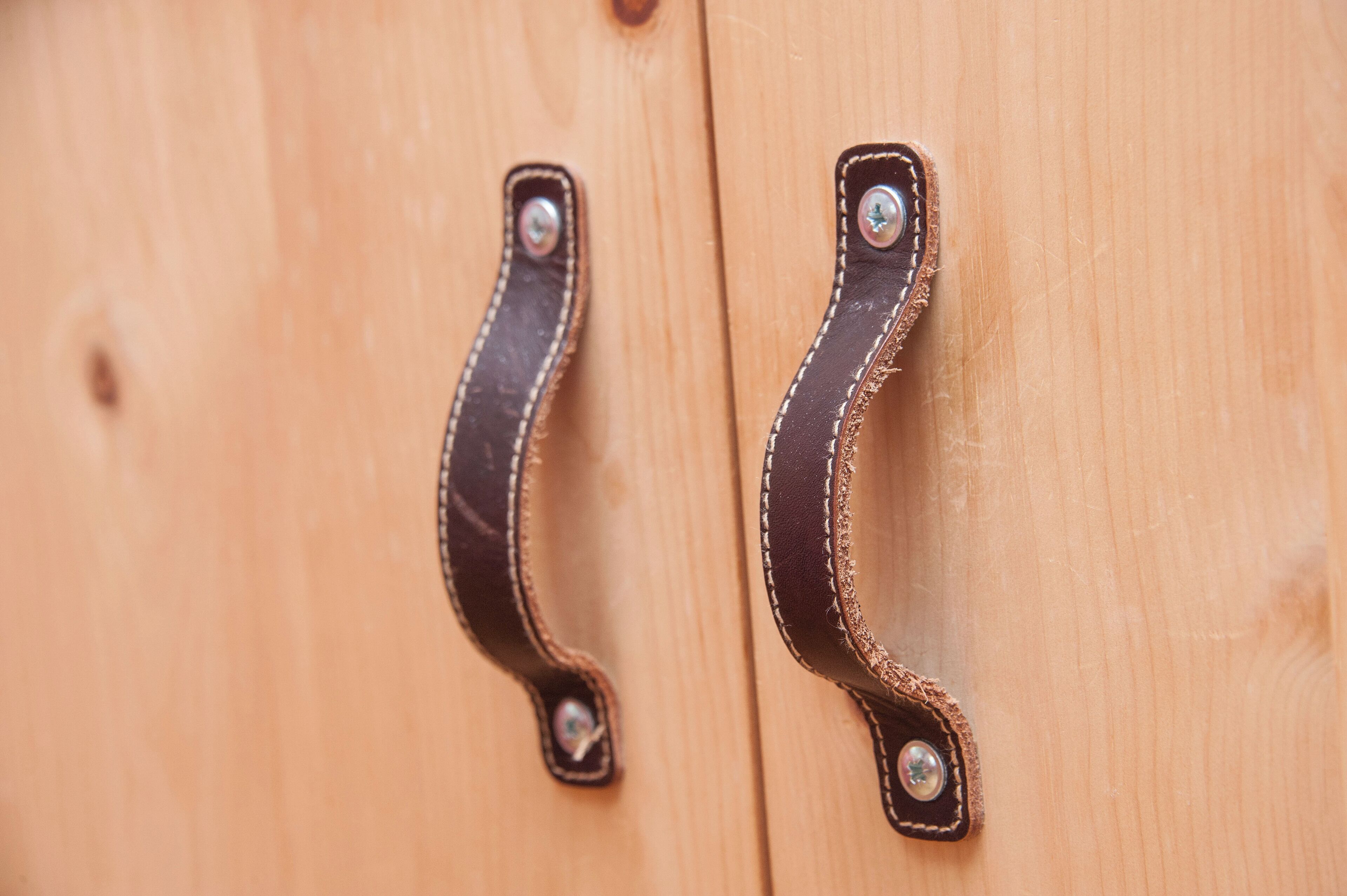 Two wooden door handles with metal screws.