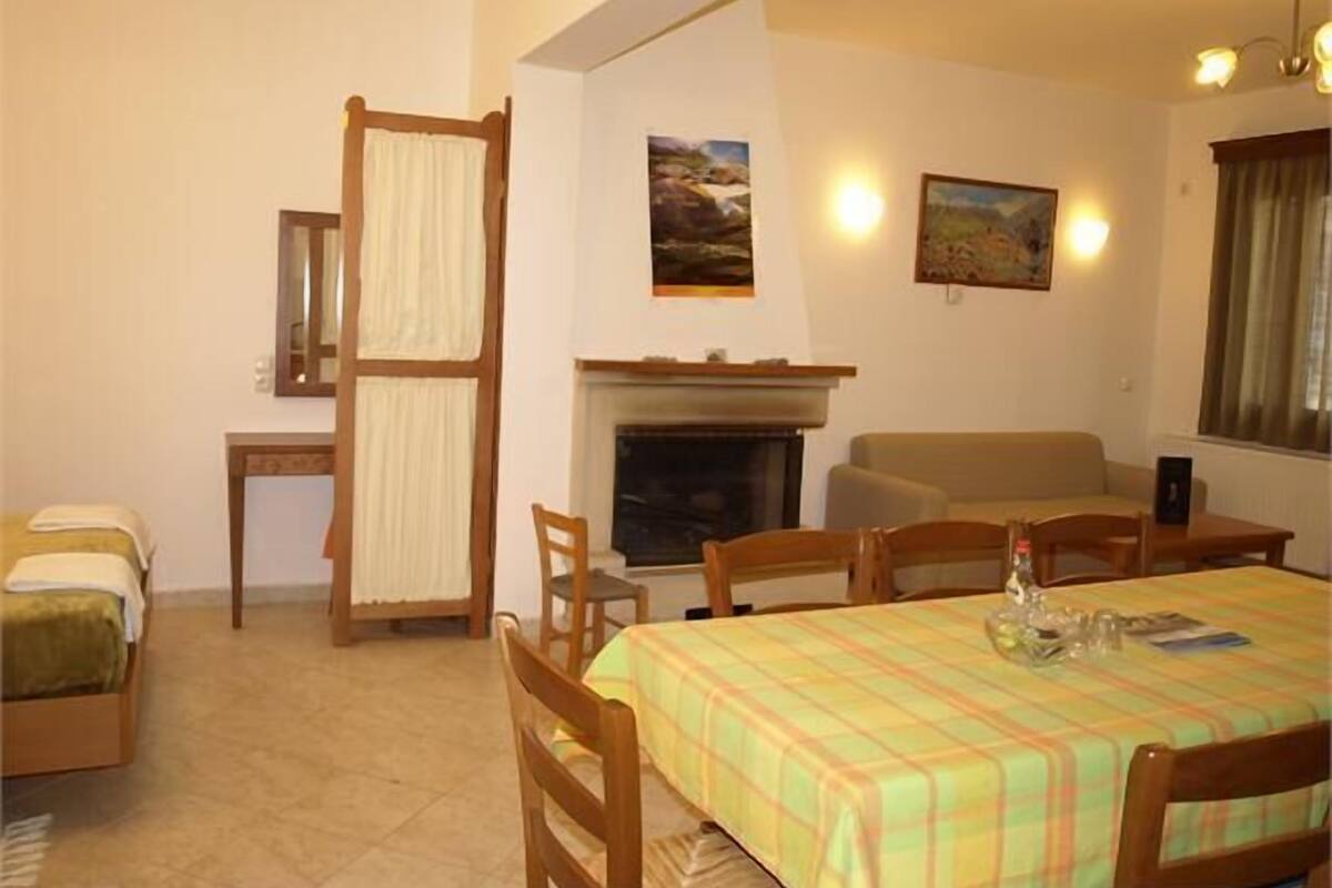A cozy room with a dining table, chairs, a sofa, a fireplace, and two framed pictures on the wall.