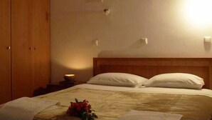 A hotel room with a bed, a nightstand, and a wall-mounted light. - Aristea Hotel (Anogia)
