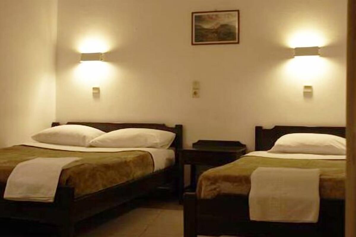 Two single beds with headboards, each with a bedside table and a wall-mounted light.