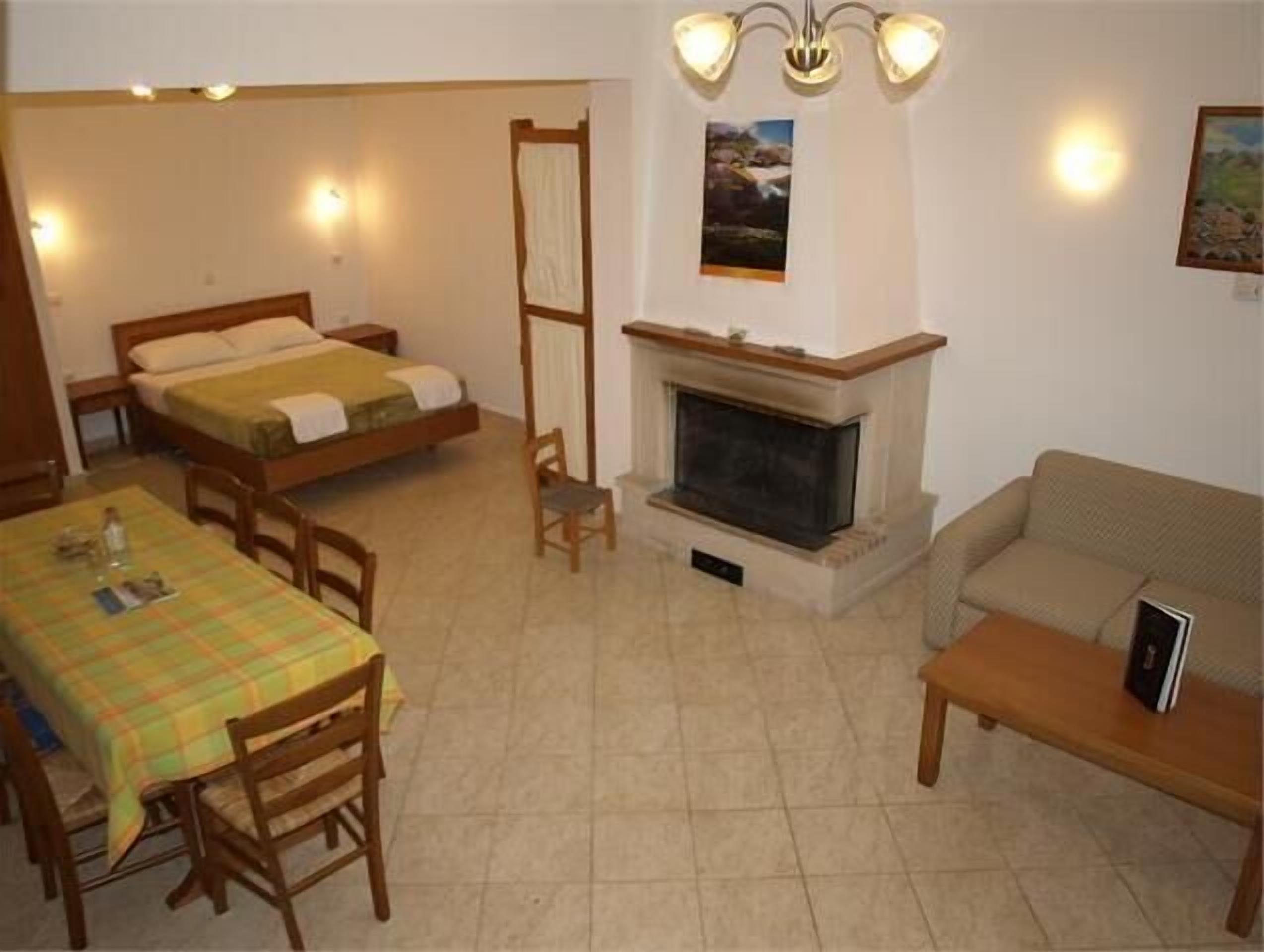 A cozy room with a bed, a fireplace, a sofa, and a dining table.