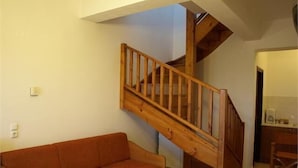 A wooden staircase in a room with a beige wall and a brown sofa. - Aristea Hotel (Anogia)