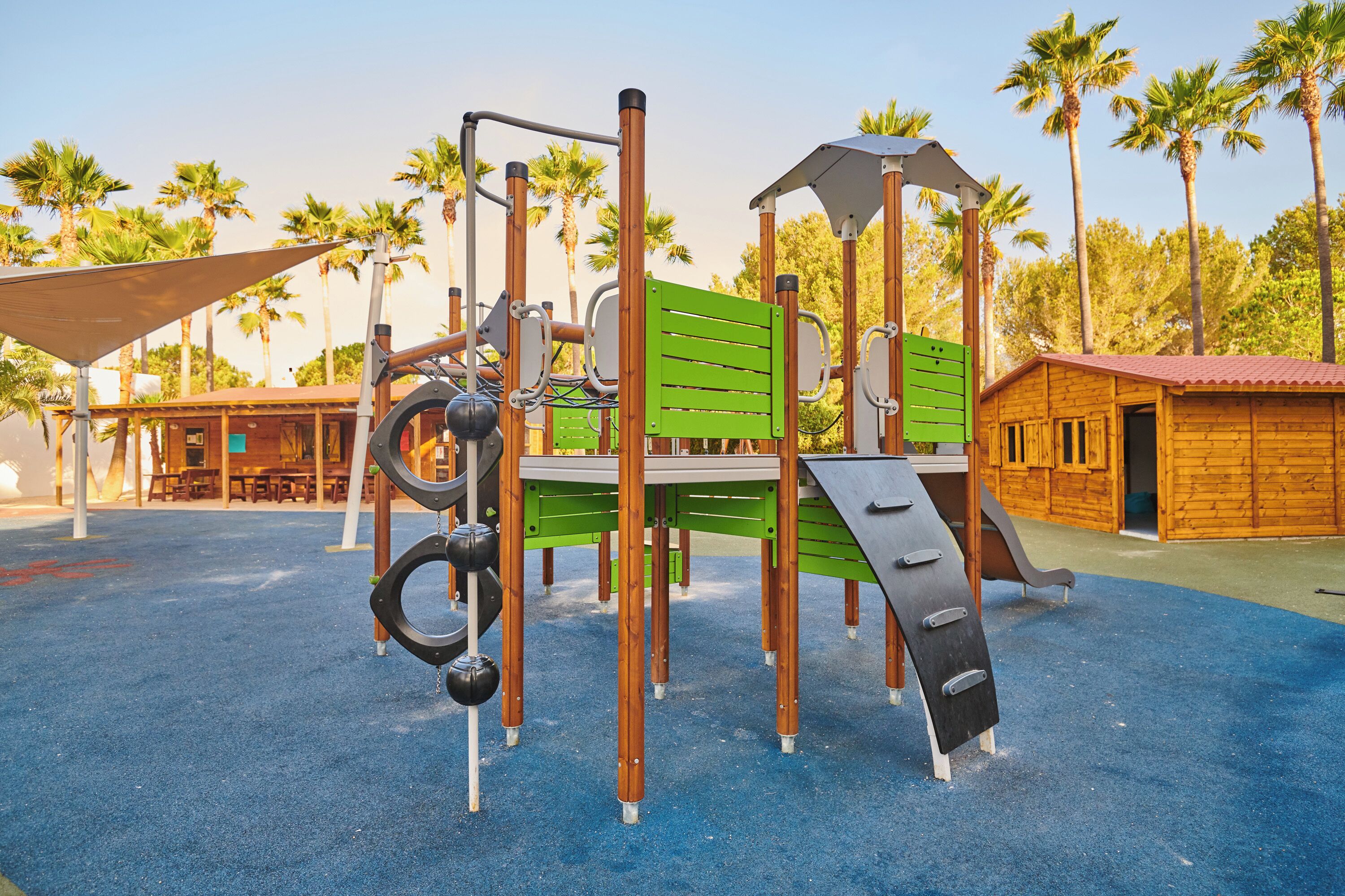 Un parque infantil con una estructura para escalar, columpios y un tobogán.