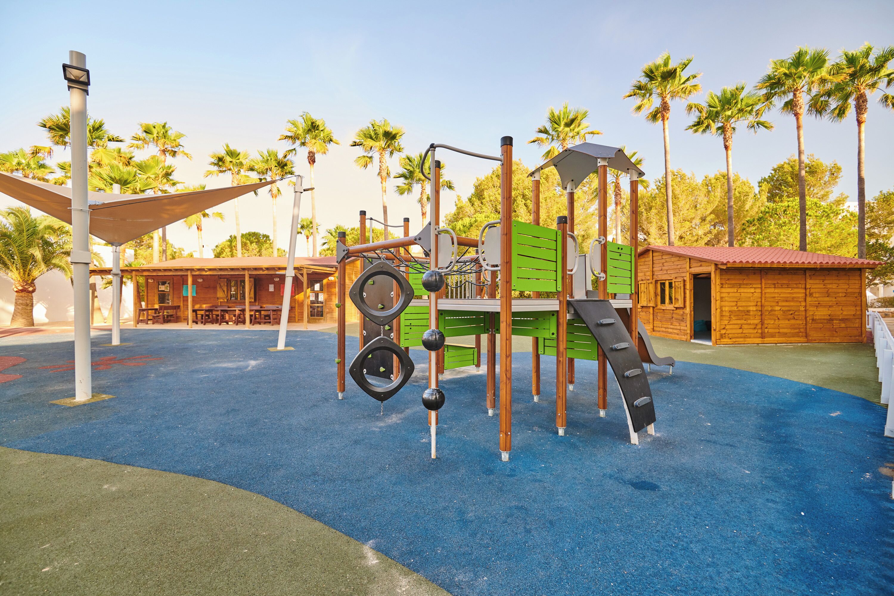 A playground with climbing structures, slides, and a covered seating area.
