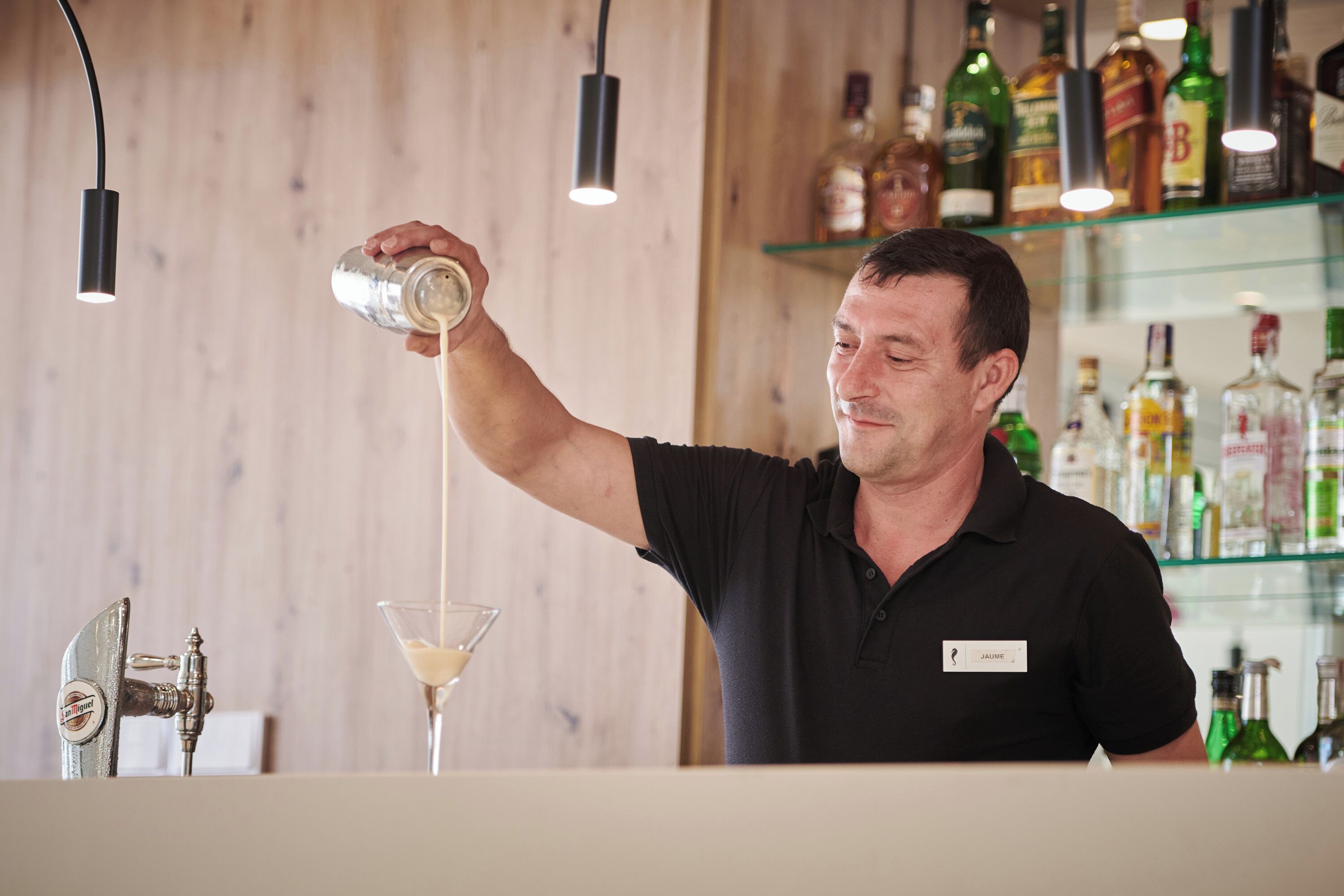 Un barman sirviendo una bebida en una copa de martini.