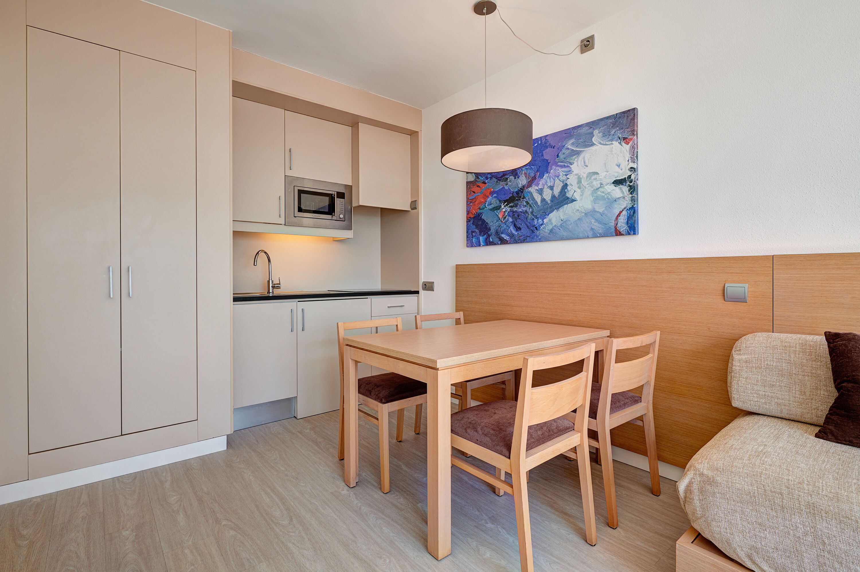 Una cocina compacta con una mesa y sillas, un microondas y un cuadro en la pared.