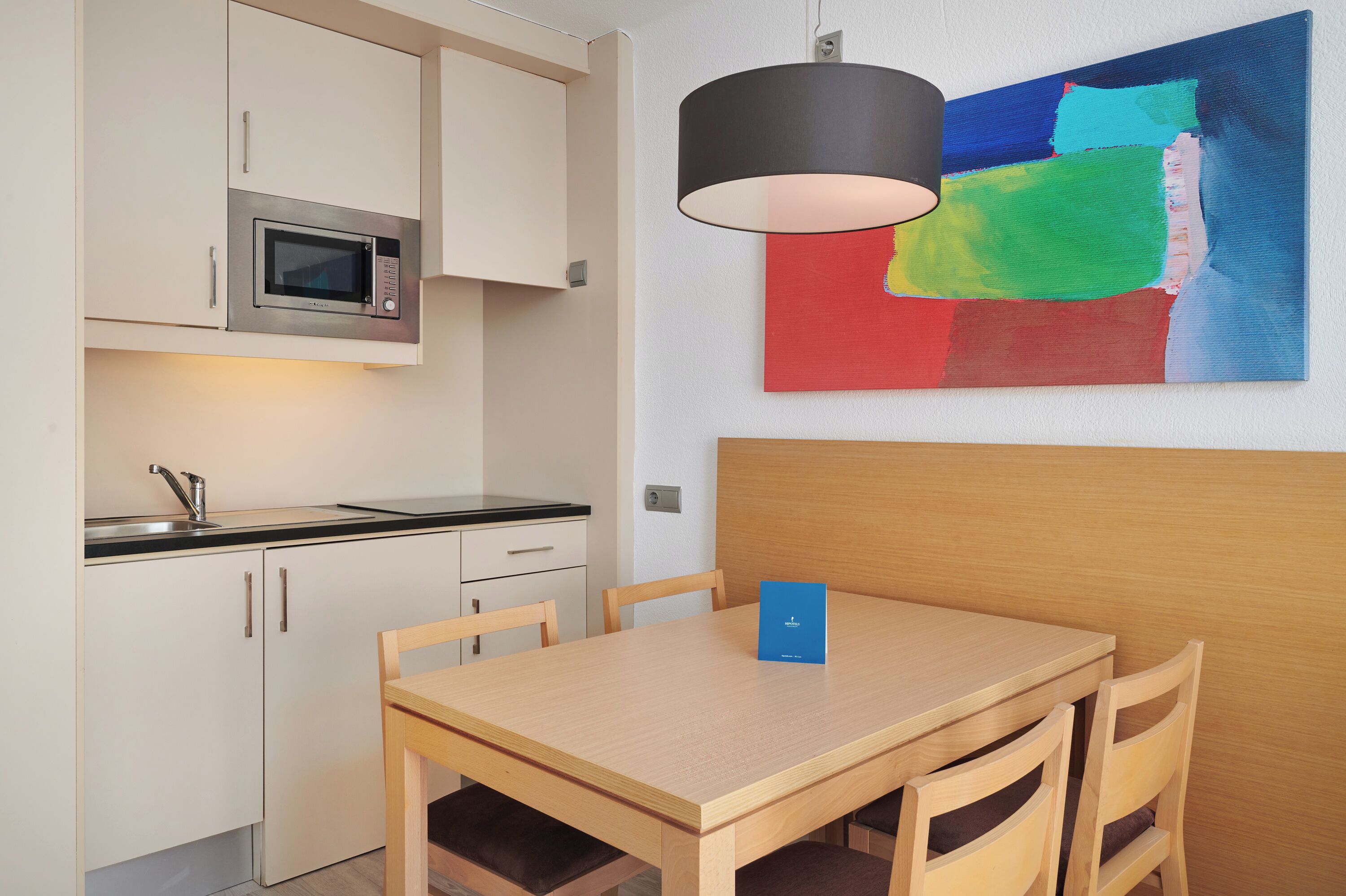 A compact kitchen with a microwave, a sink, and a dining area with a table and chairs.