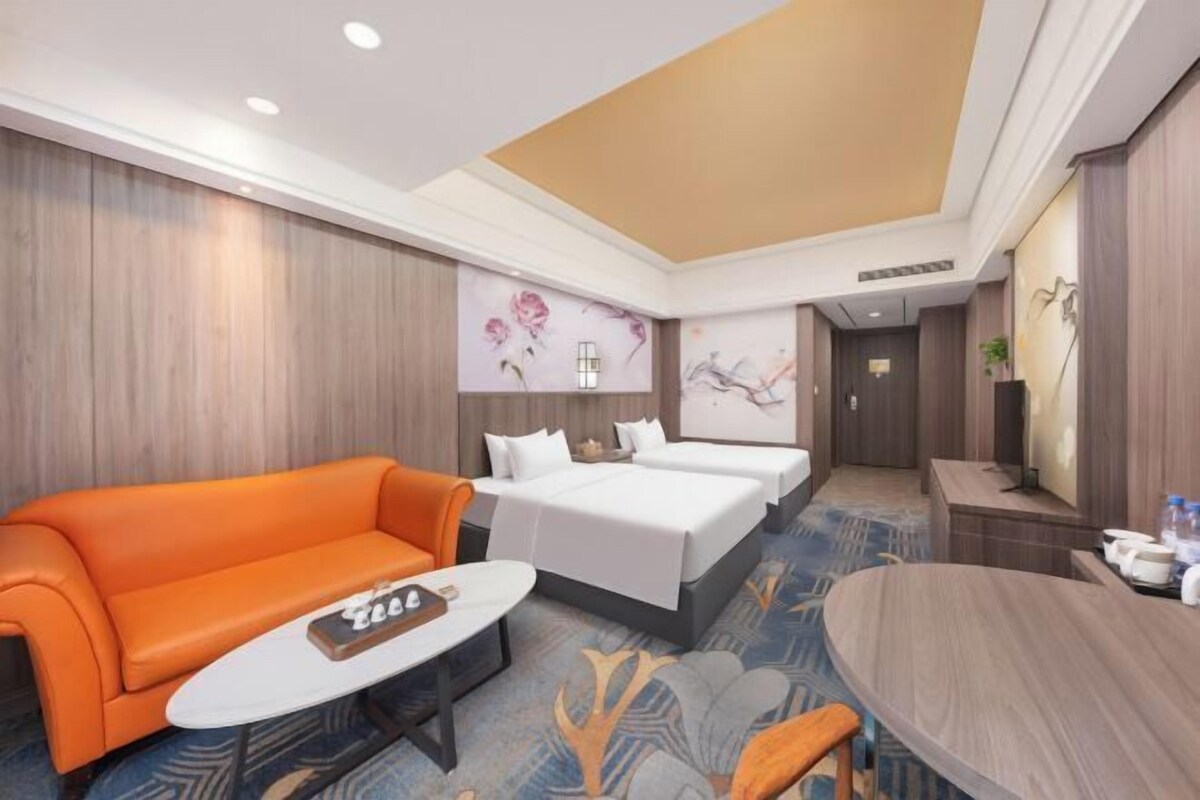 A hotel room with a sofa, a bed, a small table, and a desk.