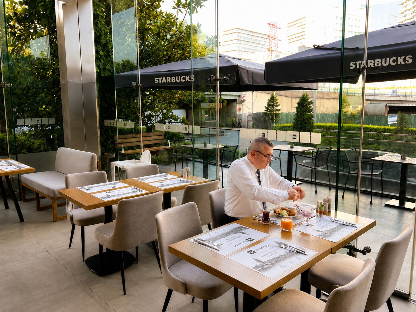 An outdoor seating area with tables and chairs, some under umbrellas, and a person dining.
