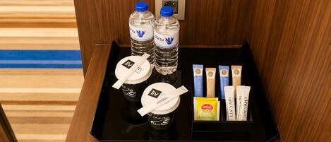 A tray with bottled water, coffee cups, and tea packets in a hotel room.