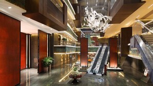 A modern hotel lobby with a central escalator, multiple levels, and a decorative light fixture. - InterContinental Changsha by IHG (Changsha)