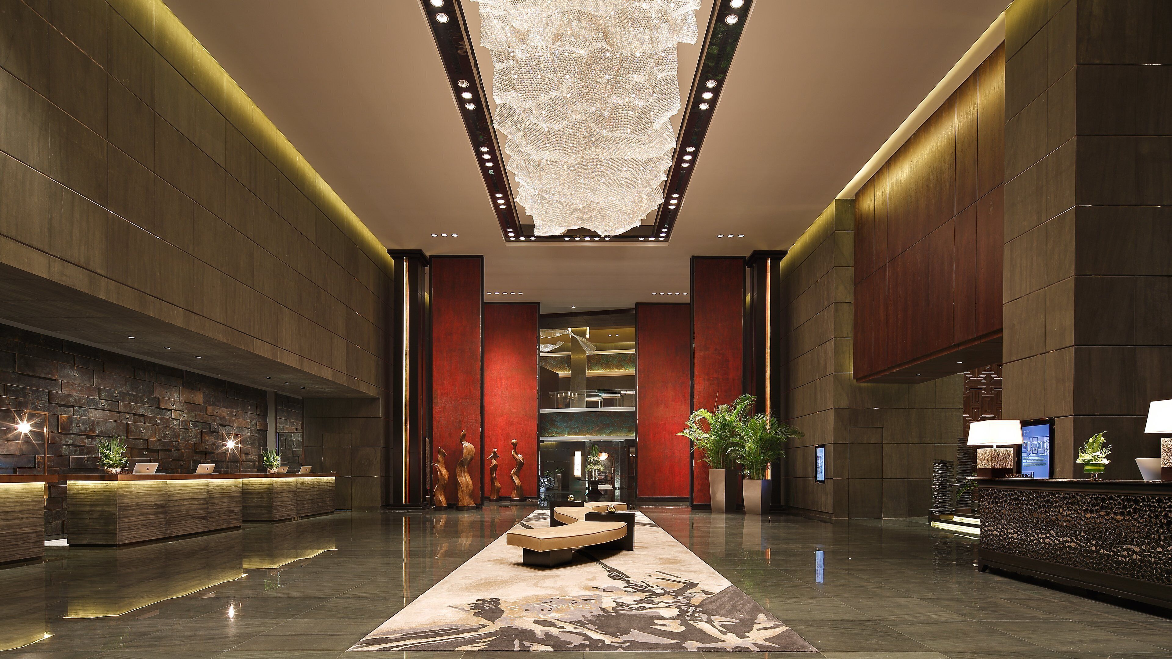 A spacious lobby with a reception desk, seating area, and a large chandelier.