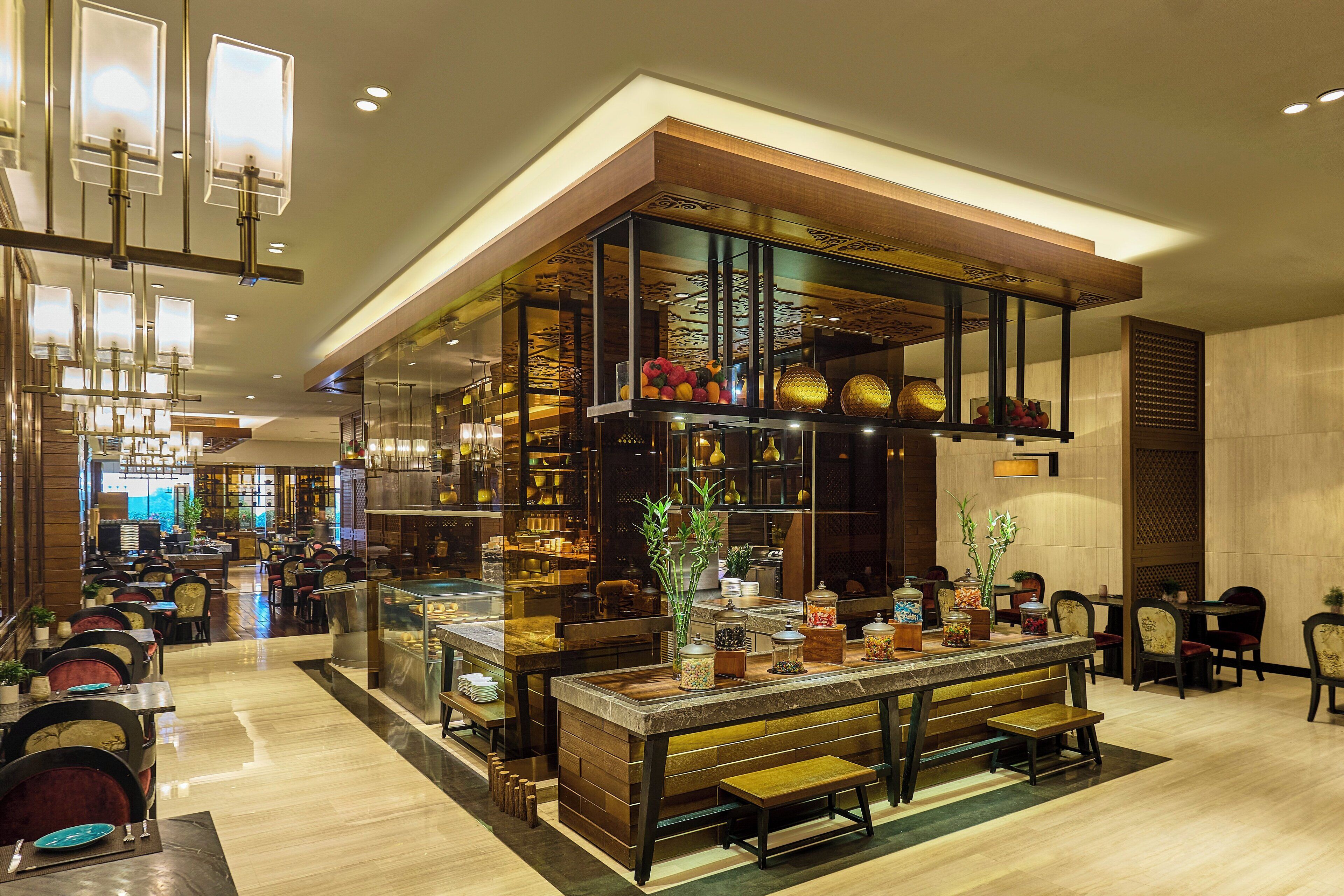 Un restaurante moderno con una barra larga, zona de estar y elementos decorativos como plantas y frascos.