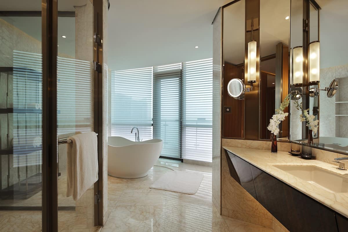 A modern bathroom with a freestanding bathtub, a large mirror, and a marble countertop.