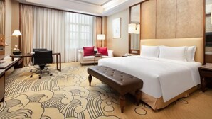 A hotel room with a large bed, a desk with a chair, a bench, a sofa with red cushions, and a large mirror. - Luxury Blue Horizon Hotel (Hot Spring Hotel) (Dongying)