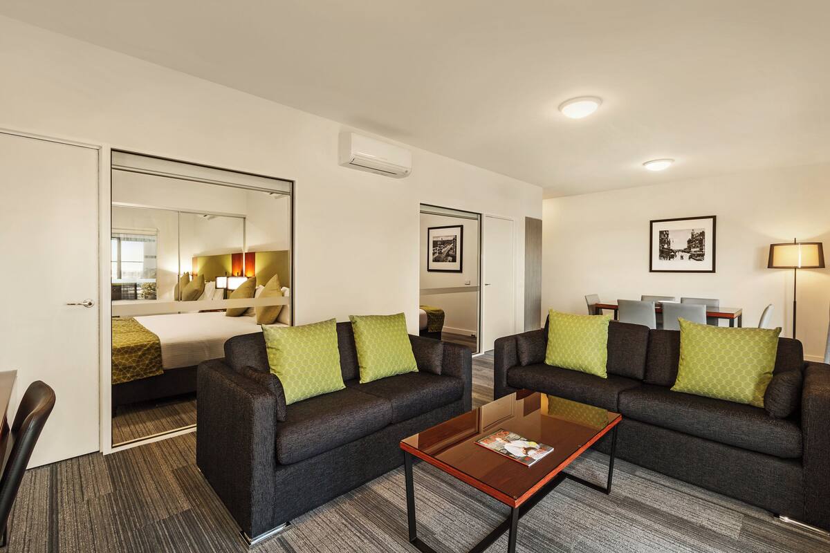Ein Hotelzimmer mit einem Bett, zwei Sofas, einem Couchtisch und einem Essbereich mit Stühlen und Tisch.