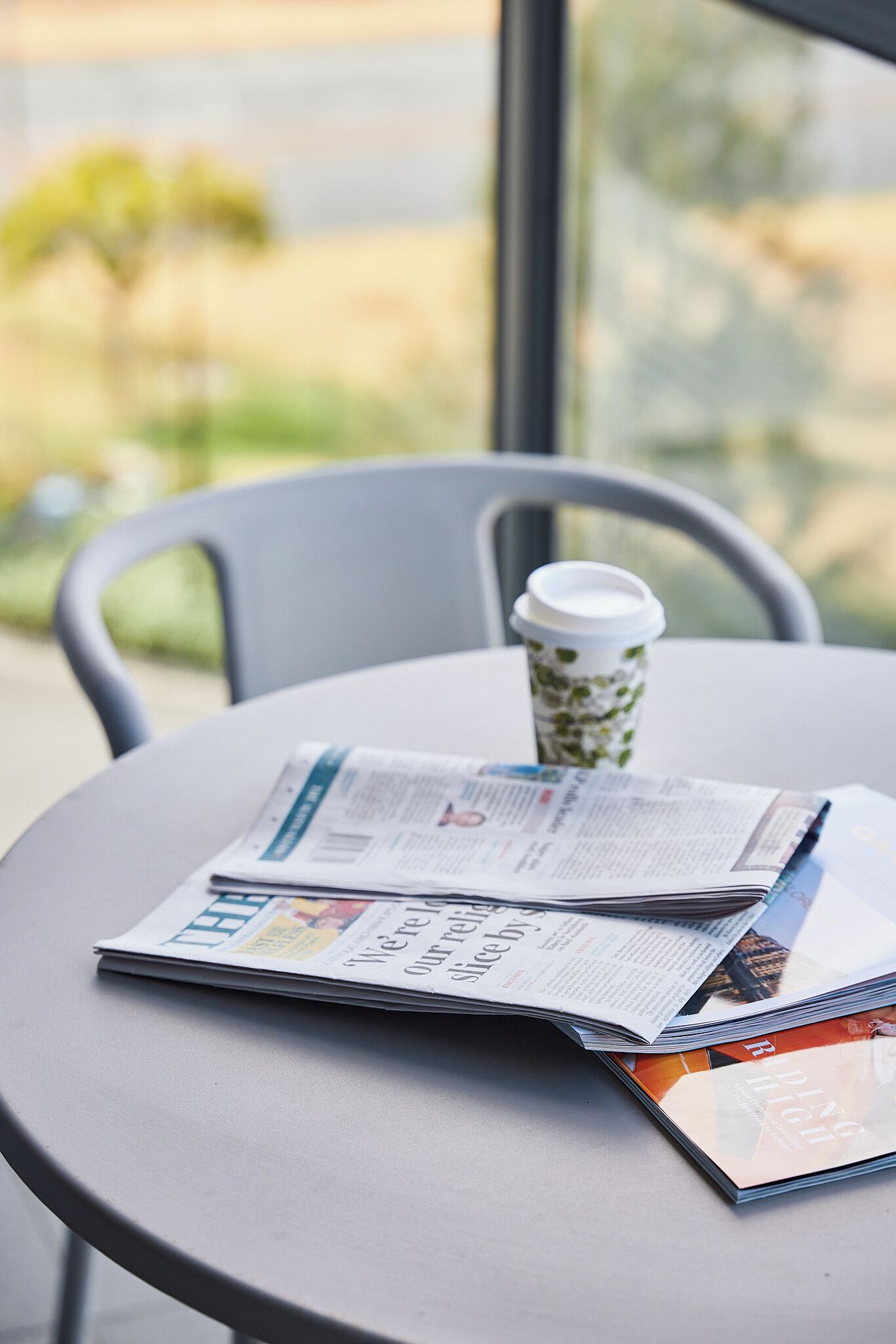 Une table avec un journal, une tasse de café et un magazine.