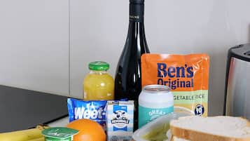 A kitchen counter with various food items and a bottle of wine.