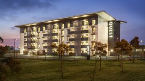 A modern multi-story hotel with a flat roof, numerous windows, and a well-lit facade. - Quest Melbourne Airport (Melbourne Airport)