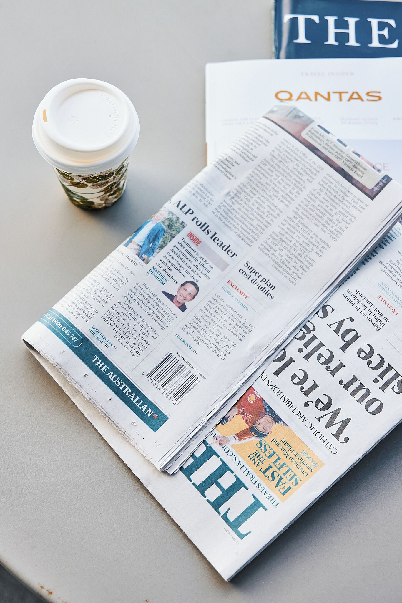 A newspaper with a coffee cup beside it.