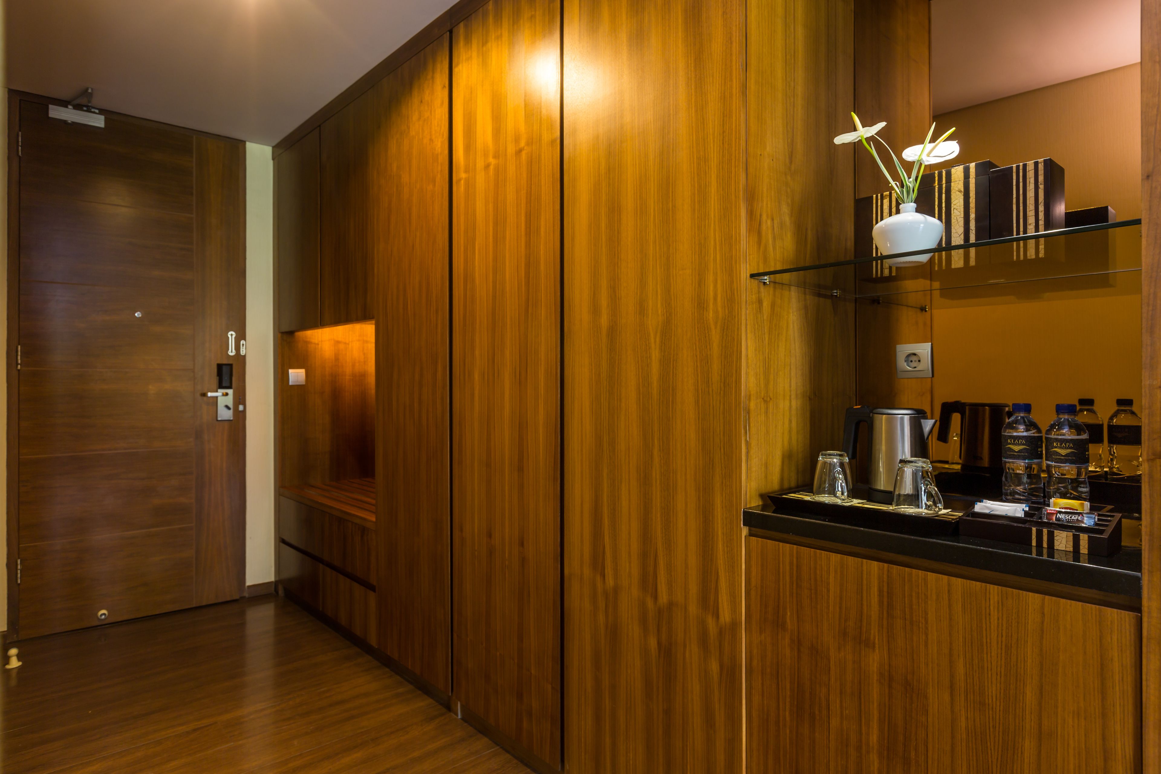 A modern kitchen with wooden cabinets, a black countertop, and a shelf with kitchen items.