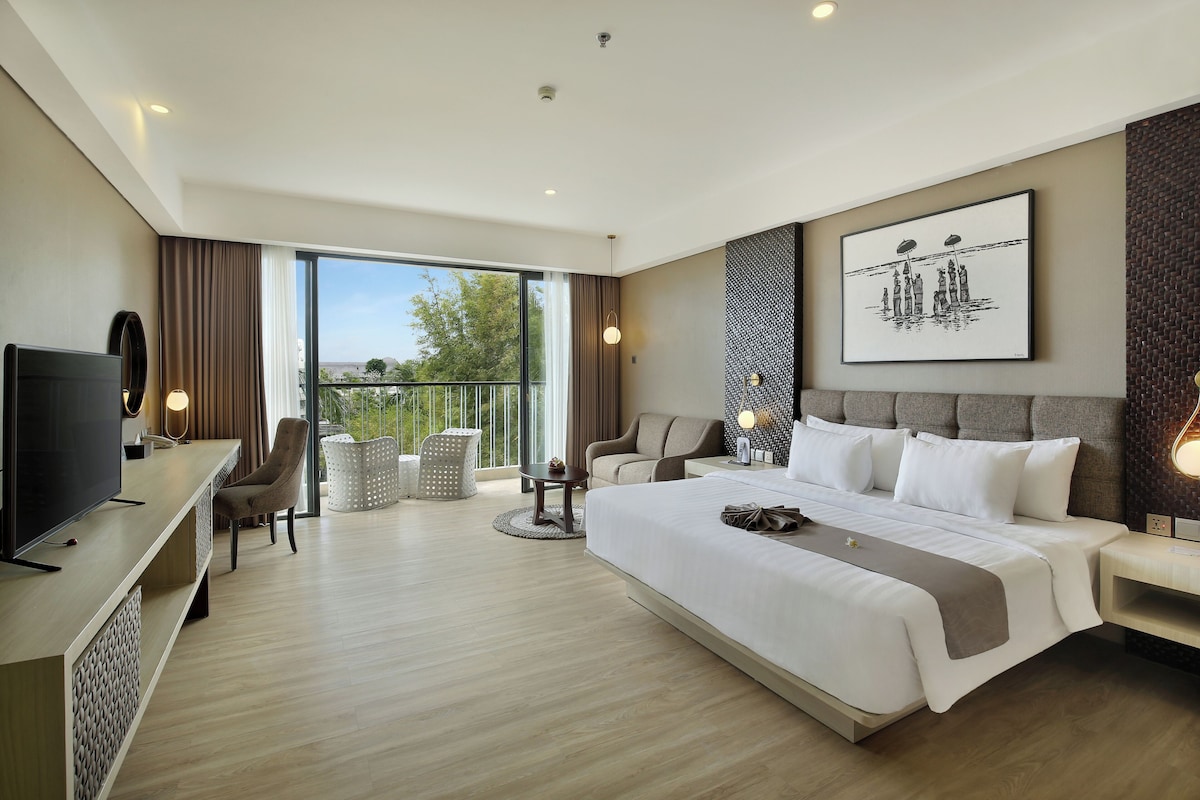 Une chambre d’hôtel moderne dotée d’un grand lit, d’une télévision, d’un canapé et d’un balcon avec vue.