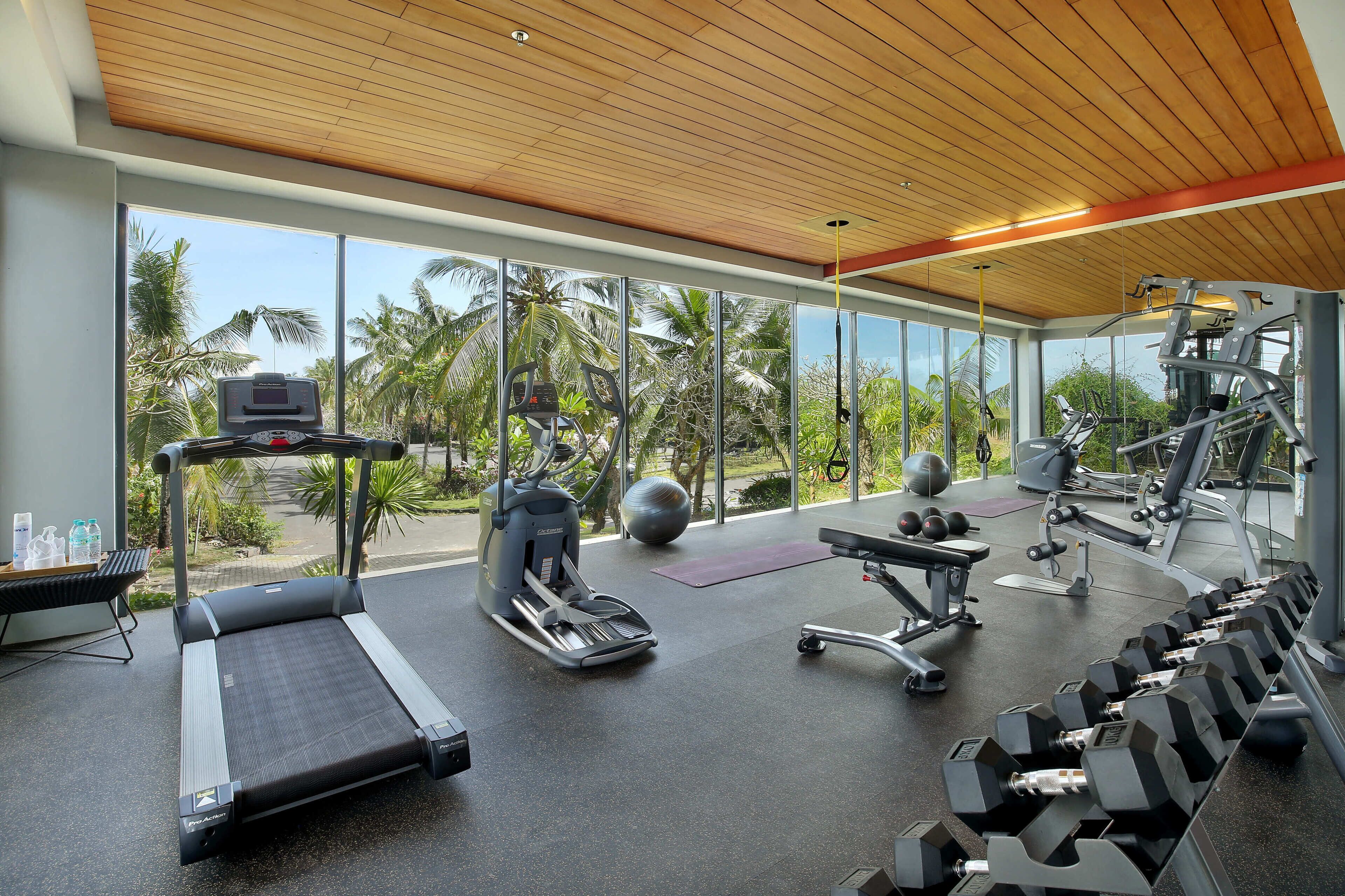 A modern gym with a treadmill, elliptical, and various weights.