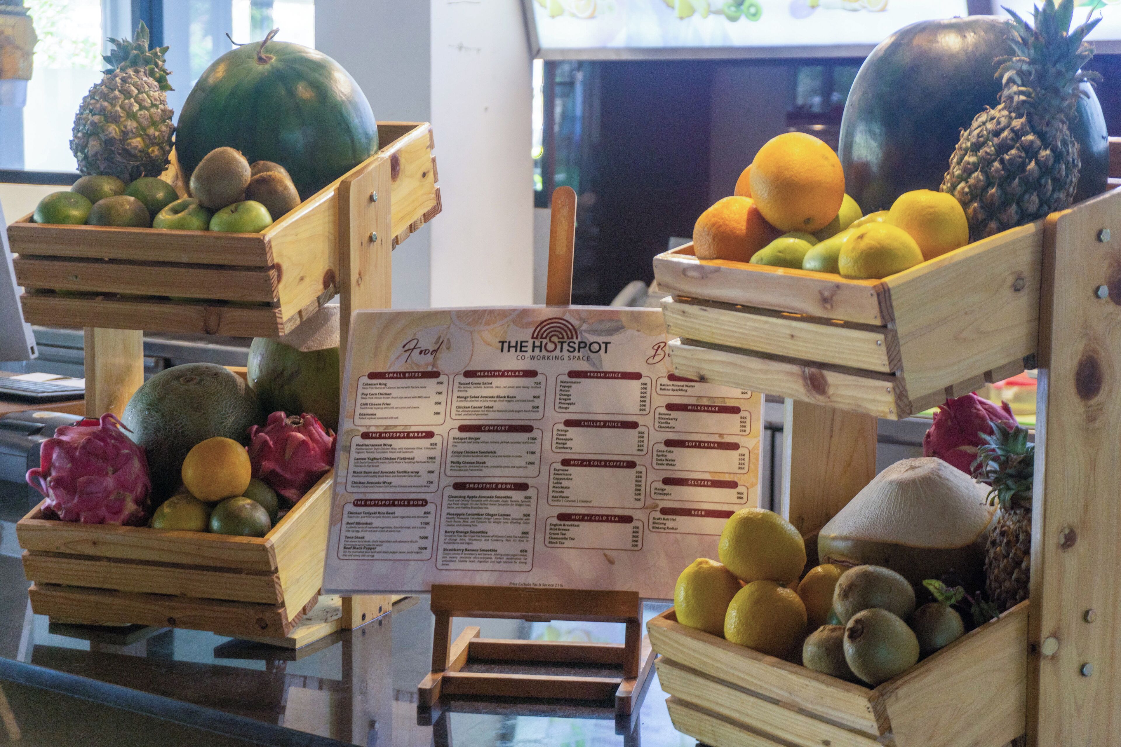 Wooden crates filled with various fruits and vegetables, a menu board in the center, and a small wooden stool.