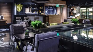 Ett modernt loungeområde med sittplatser, en bar och en pool.