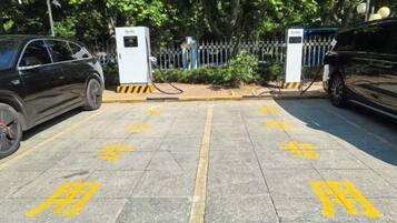 A parking area with electric vehicle charging stations and a gated entrance.
