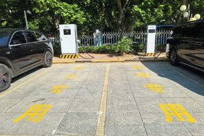 A parking area with electric vehicle charging stations and a gated entrance. - Aulicare Hotel (Dalian)